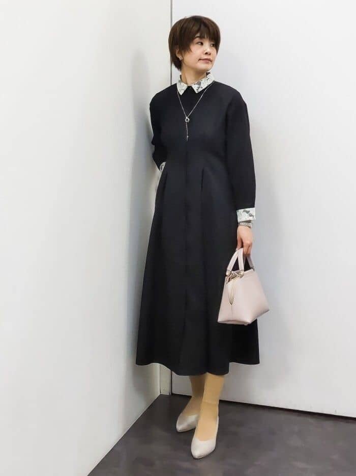 ホワイト系のノーカラージャケット、ブラック系のワンピース、ピンク系のハンドバッグを着用したレディースの冬コーディネートの6枚目の写真