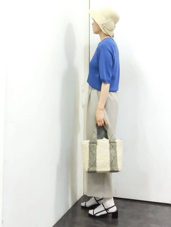ブルー系のニット/セーター、ベージュ系のその他パンツ、ホワイト系のトートバッグを着用したレディースの春コーディネートの2枚目の写真