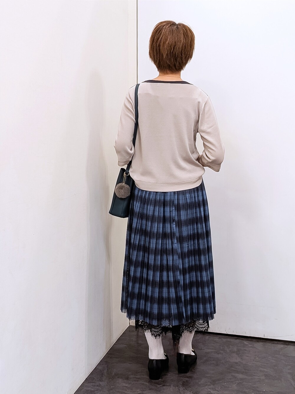 ベージュ系のニット/セーター、ホワイト系のTシャツ/カットソー、ブルー系のスカートを着用したレディースの秋コーディネートの3枚目の写真