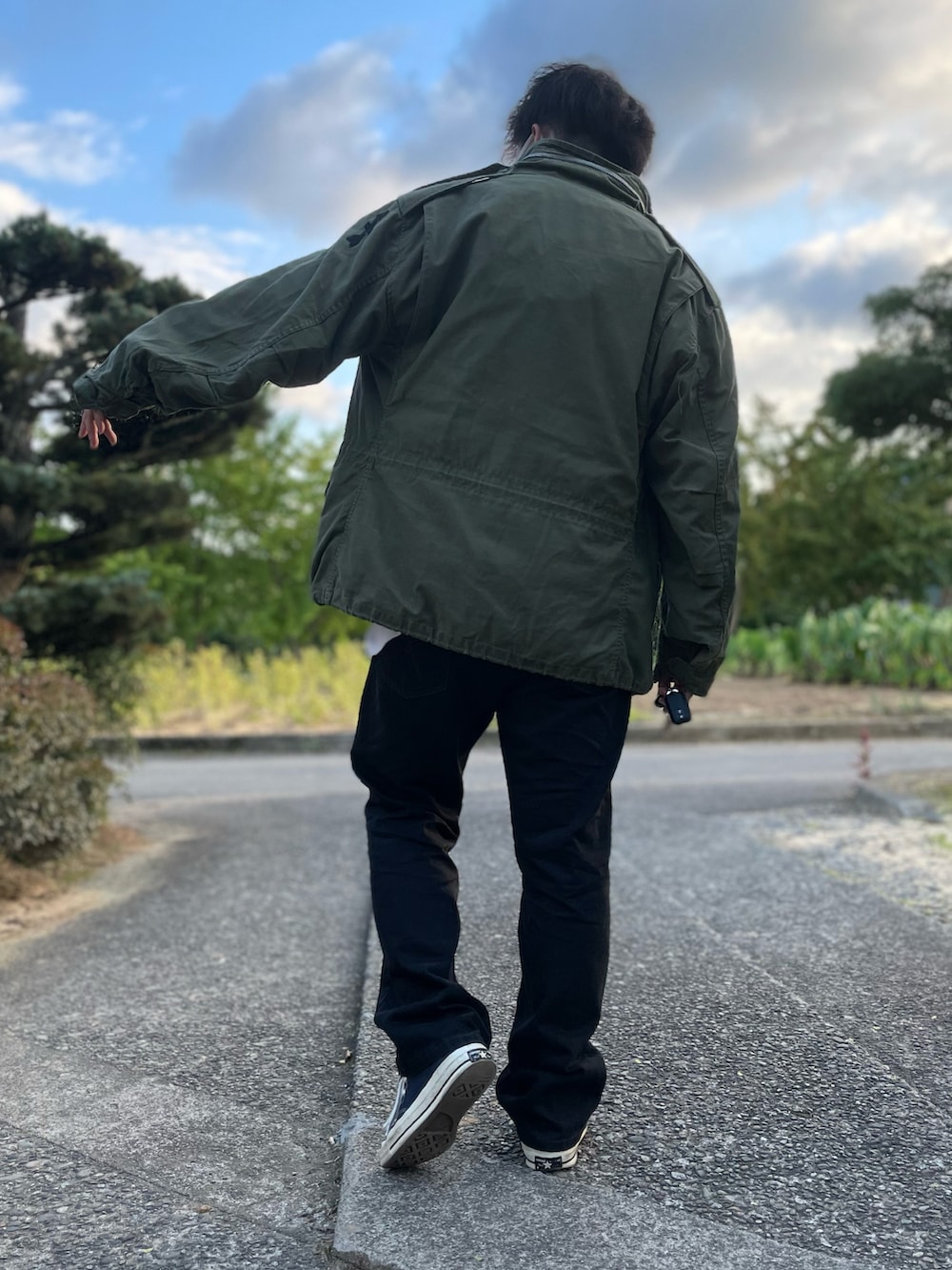 グリーン系のミリタリージャケット、パープル系のニット/セーター、ブラック系のデニムパンツを着用したメンズの秋コーディネートの2枚目の写真