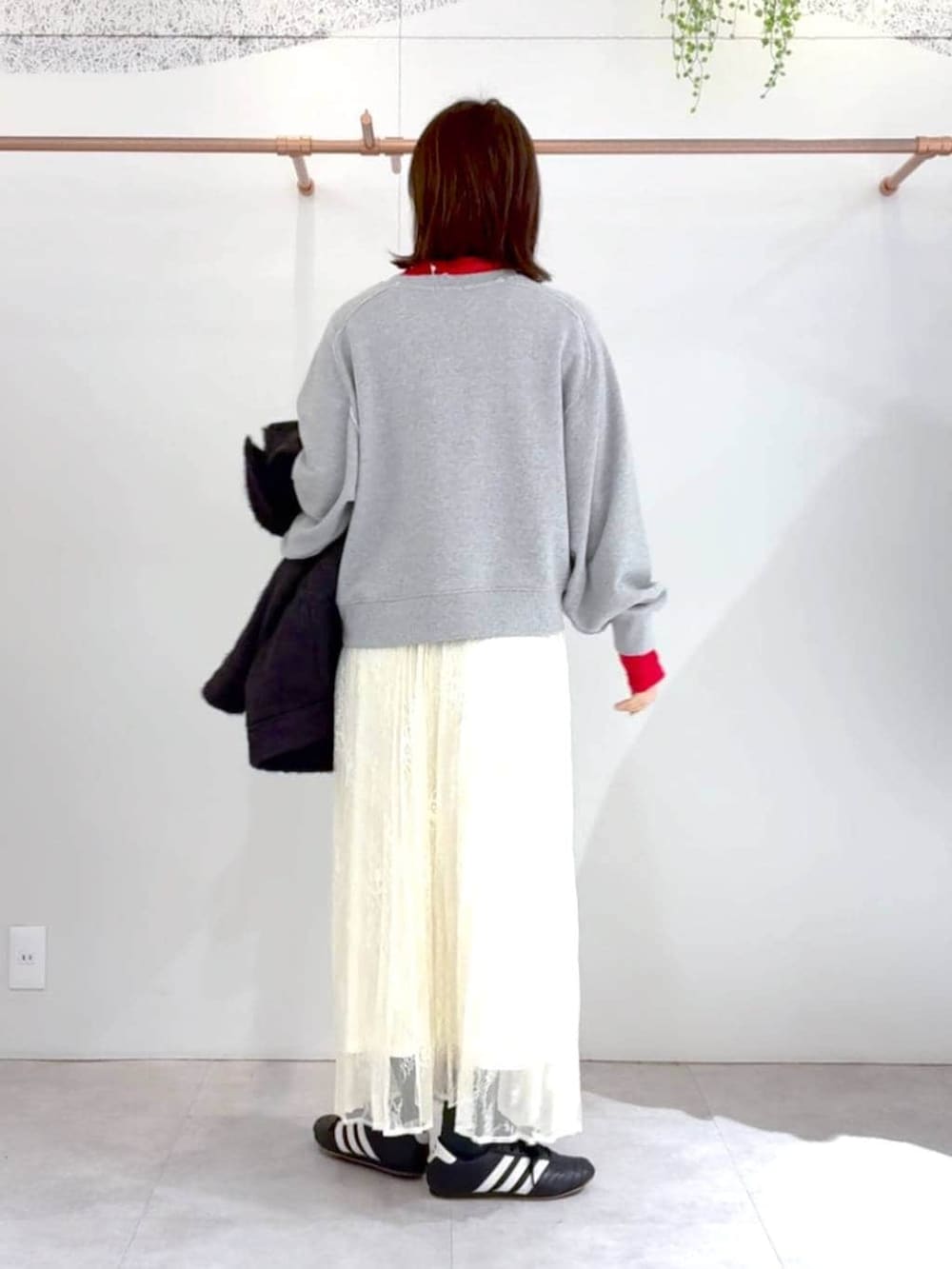 レッド系のTシャツ/カットソー、ブラック系のボストンバッグ、ホワイト系のスカートを着用したレディースの冬コーディネートの2枚目の写真