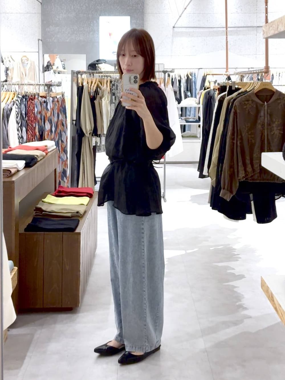 ブラック系のパンプス、ブラウン系のショルダーバッグ、ブルー系のデニムパンツを着用したレディースの春コーディネートの2枚目の写真