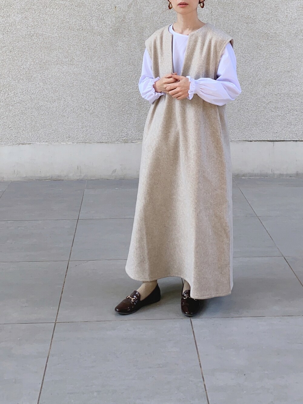 ベージュ系のワンピース、ブラック系のベスト、ブラウン系のレインシューズを着用したレディースの秋コーディネートの5枚目の写真