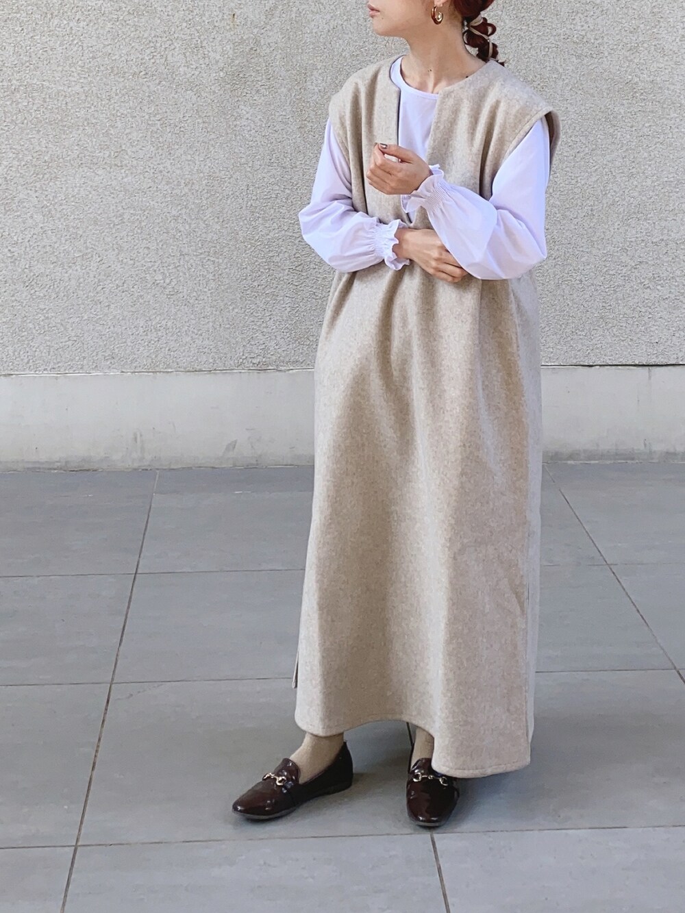 ベージュ系のワンピース、ブラック系のベスト、ブラウン系のレインシューズを着用したレディースの秋コーディネートの4枚目の写真