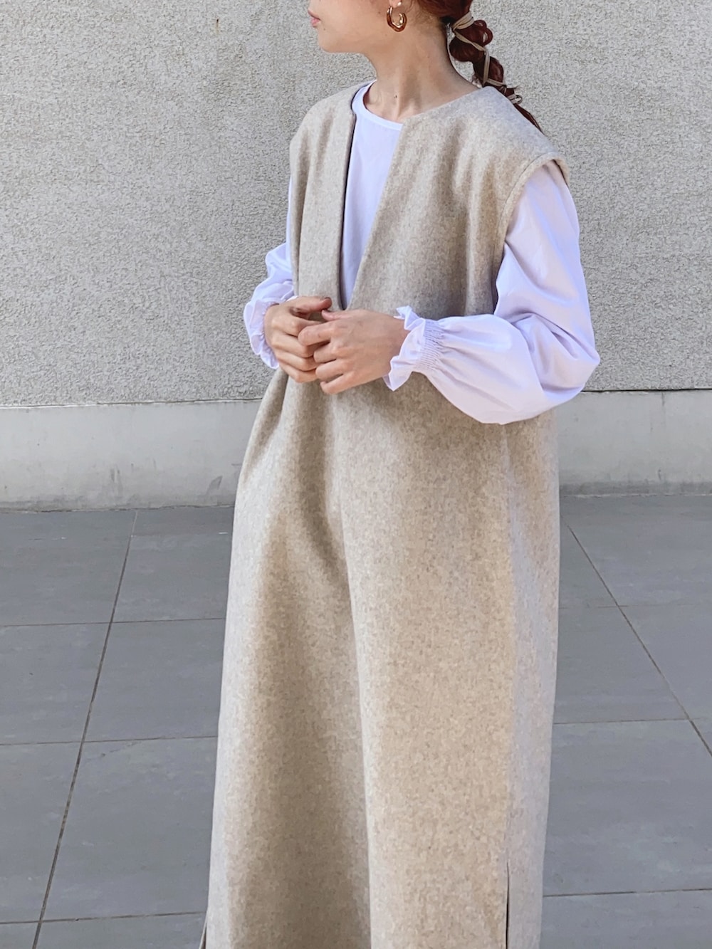 ベージュ系のワンピース、ブラック系のベスト、ブラウン系のレインシューズを着用したレディースの秋コーディネートの3枚目の写真