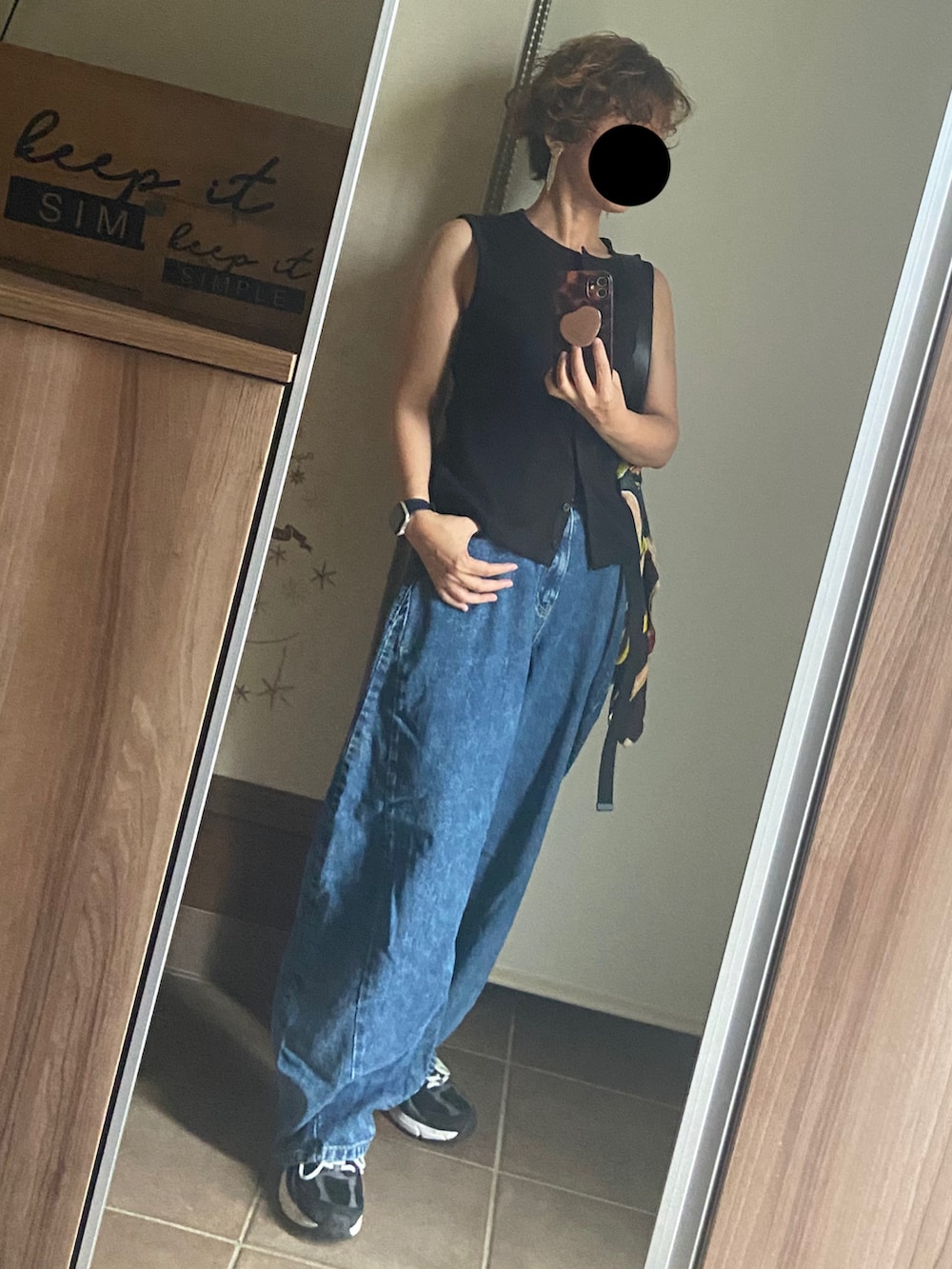 ブラック系のベスト、ブルー系のデニムパンツ、ブラック系のショルダーバッグを着用したレディースの夏コーディネートの2枚目の写真