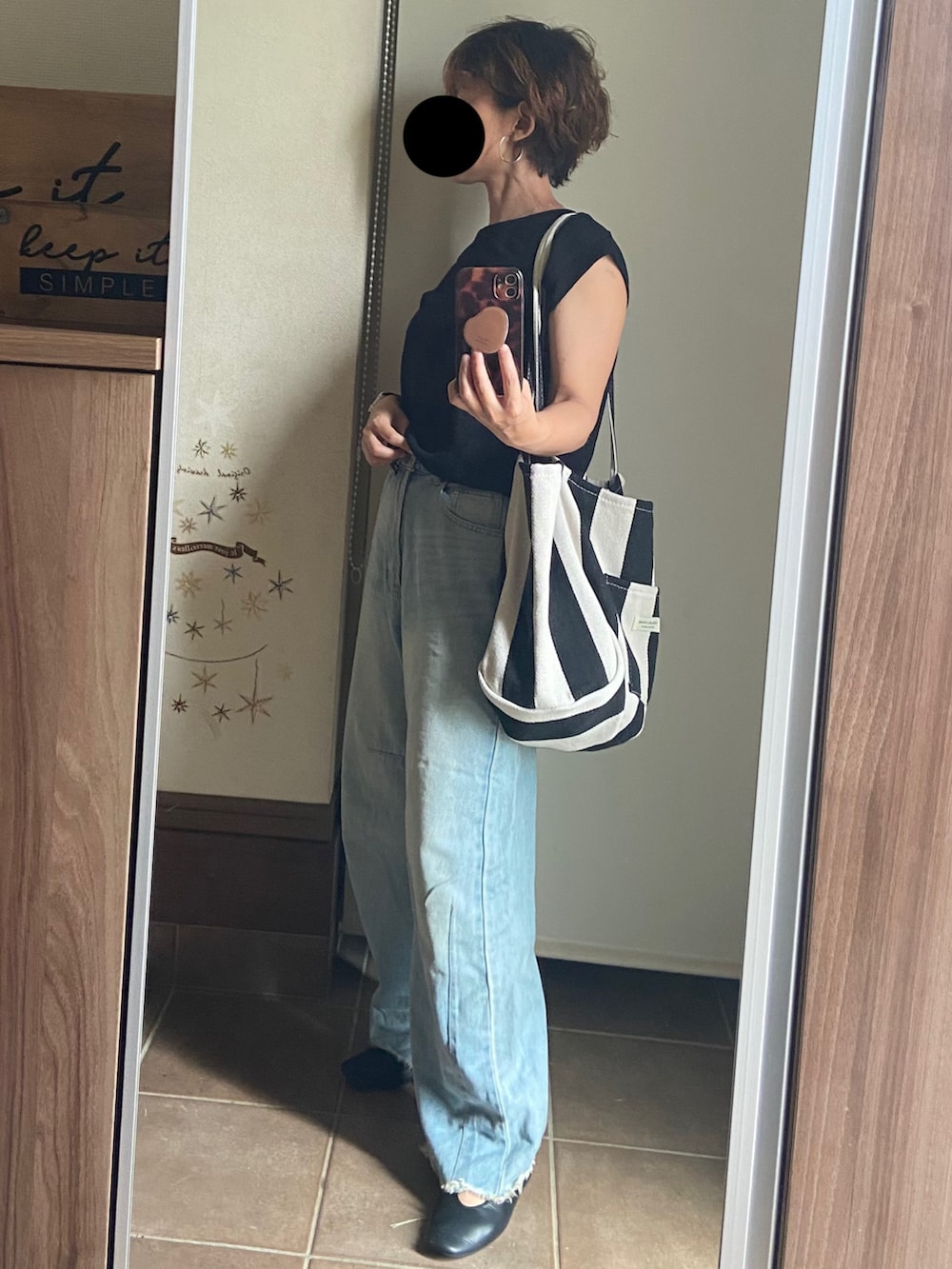 ブラック系のニット/セーター、ブルー系のデニムパンツ、ブラック系のトートバッグを着用したレディースの夏コーディネートの2枚目の写真