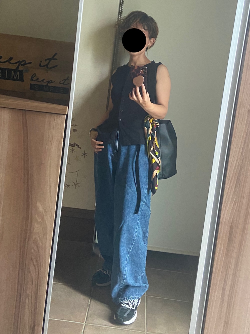 ブラック系のベスト、ブルー系のデニムパンツ、ブラック系のショルダーバッグを着用したレディースの夏コーディネートの3枚目の写真