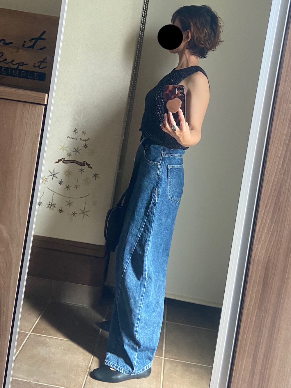 ブルー系のデニムパンツ、ブラック系のバッグ、ブラック系のベストを着用したレディースの夏コーディネートの2枚目の写真