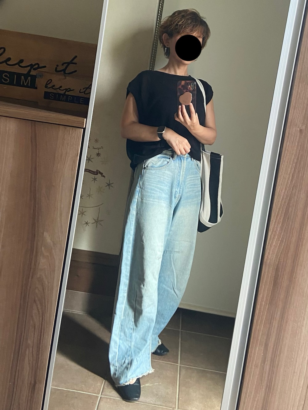 ブラック系のニット/セーター、ブルー系のデニムパンツ、ブラック系のトートバッグを着用したレディースの夏コーディネートの3枚目の写真