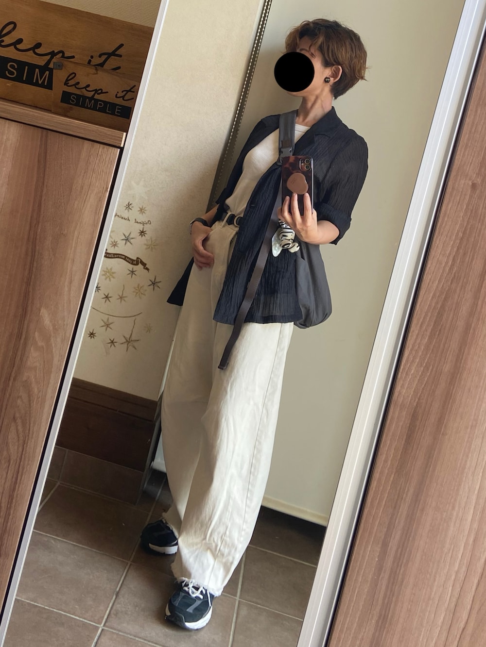 ブラック系のテーラードジャケット、ホワイト系のデニムパンツ、ブラック系のスニーカーを着用したレディースの夏コーディネートの3枚目の写真