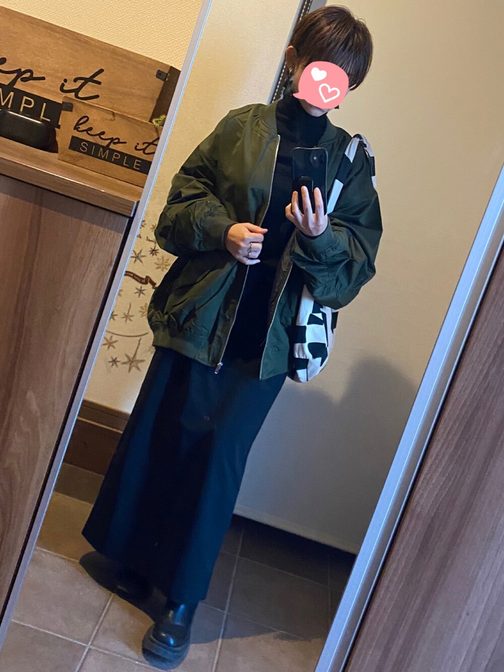 グリーン系のMA-1、ブラック系のスカート、ブラック系のブーツを着用したレディースの冬コーディネートの3枚目の写真