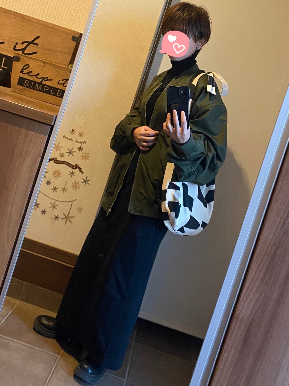 グリーン系のMA-1、ブラック系のスカート、ブラック系のブーツを着用したレディースの冬コーディネートの2枚目の写真