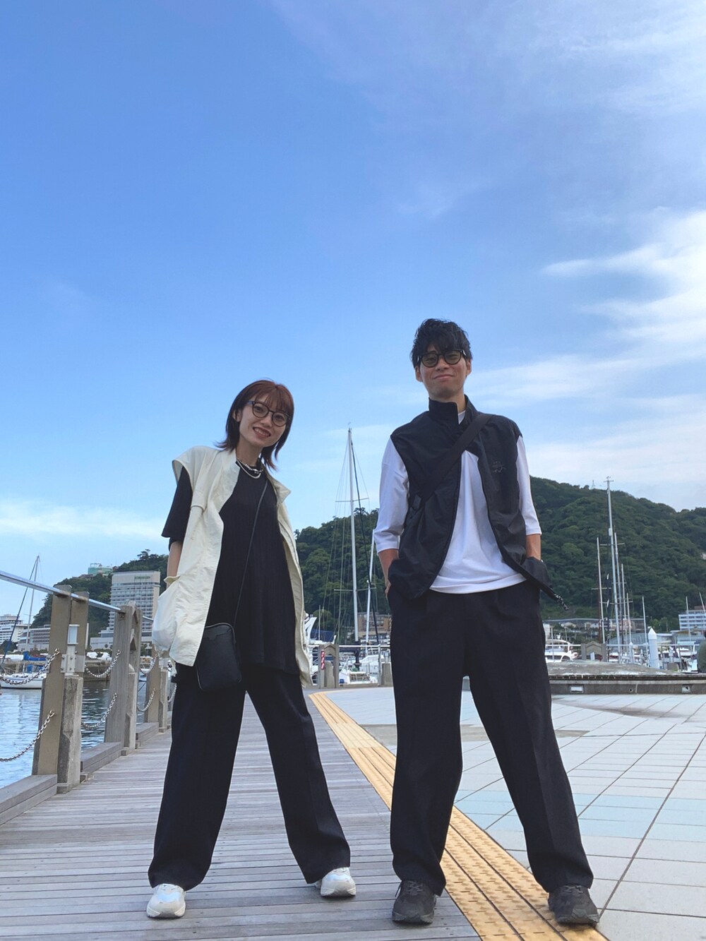 ブラック系のスラックス、ブルー系のスニーカー、シルバー系のネックレスを着用したレディースの夏コーディネートの2枚目の写真