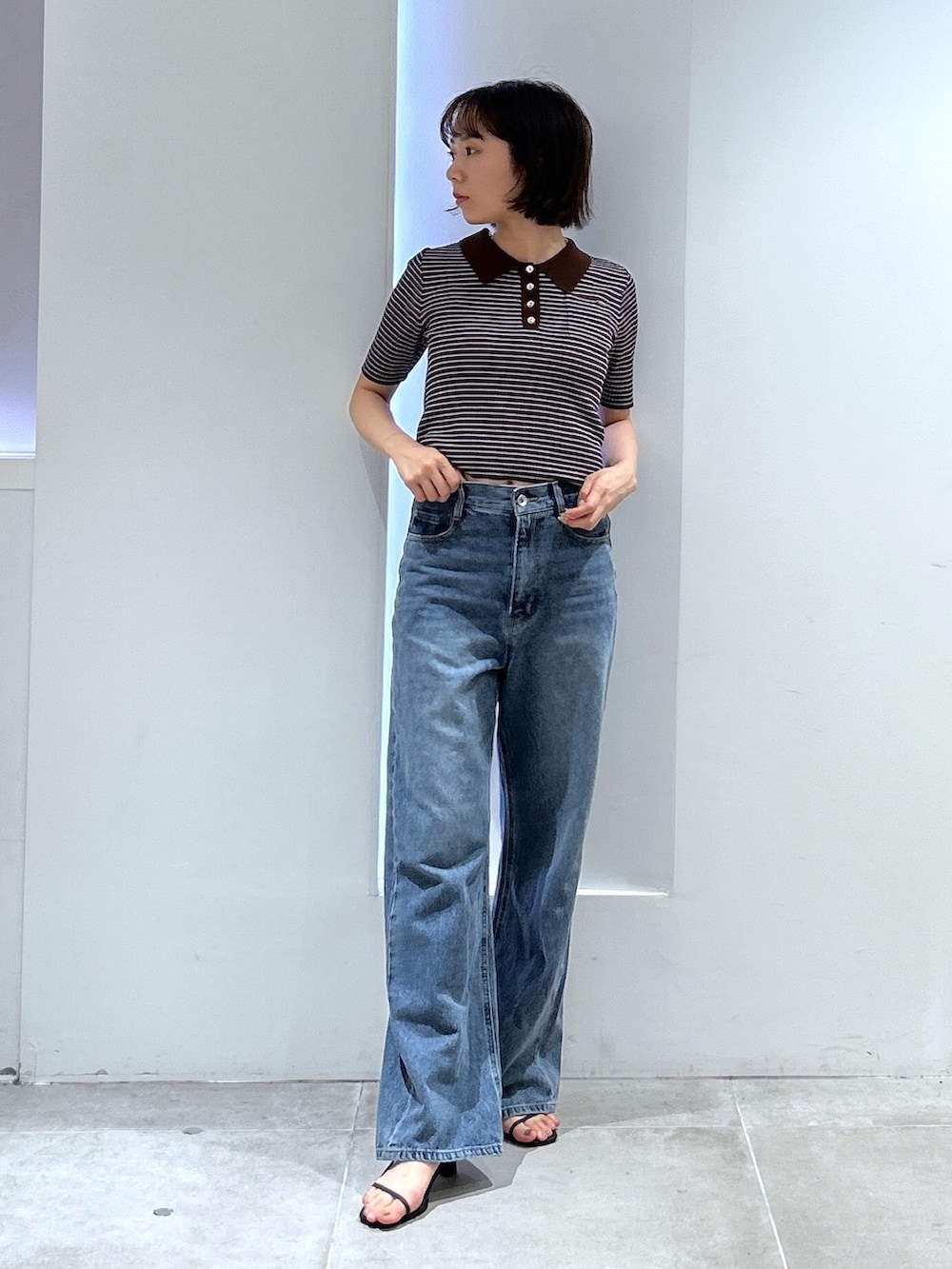 ブルー系のデニムパンツ、ブラウン系のワンピースを着用したレディースの夏コーディネートの2枚目の写真