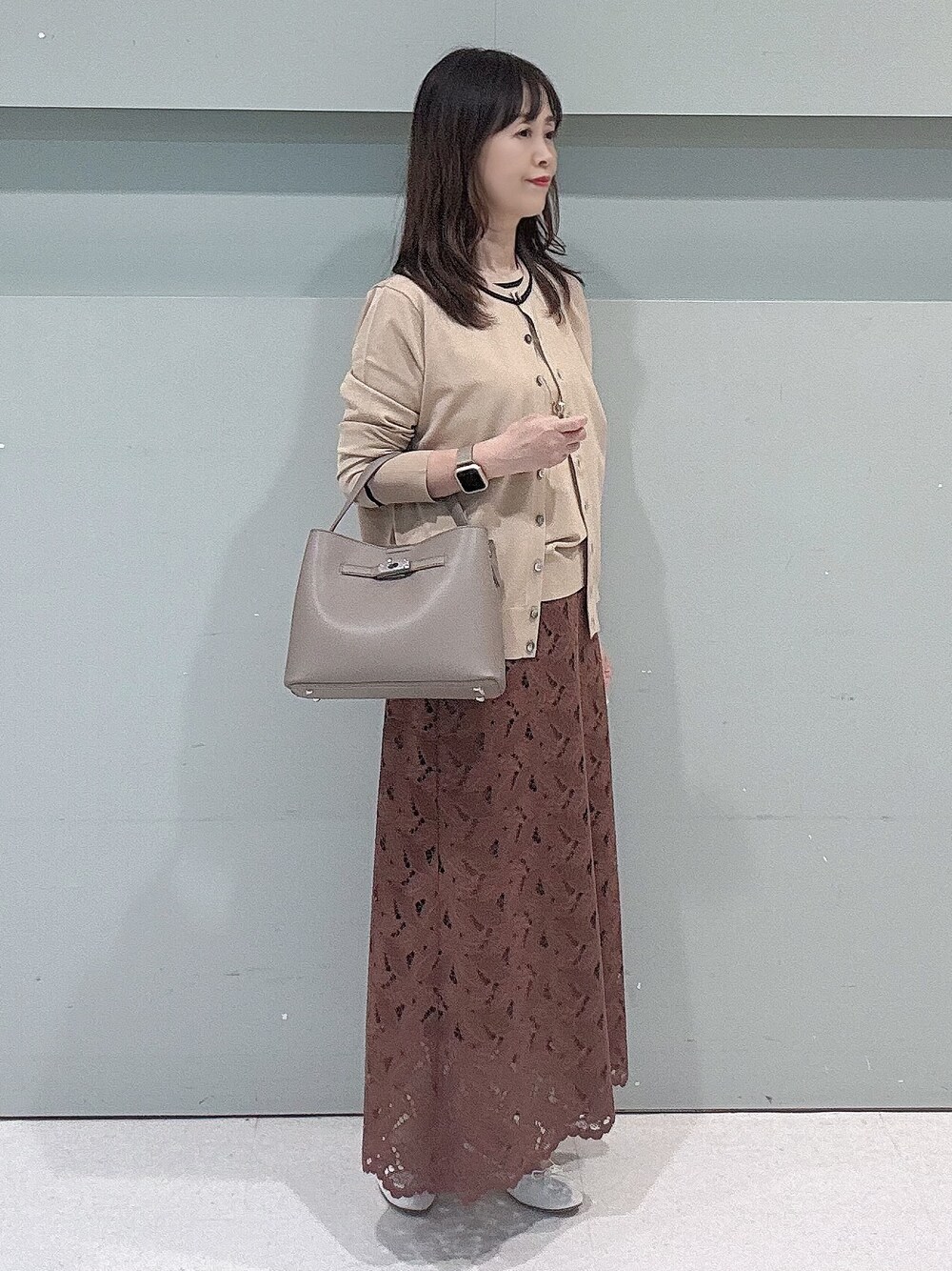 ベージュ系のカーディガン/ボレロ、ベージュ系のニット/セーター、ブラウン系のスカートを着用したレディースの秋コーディネートの3枚目の写真