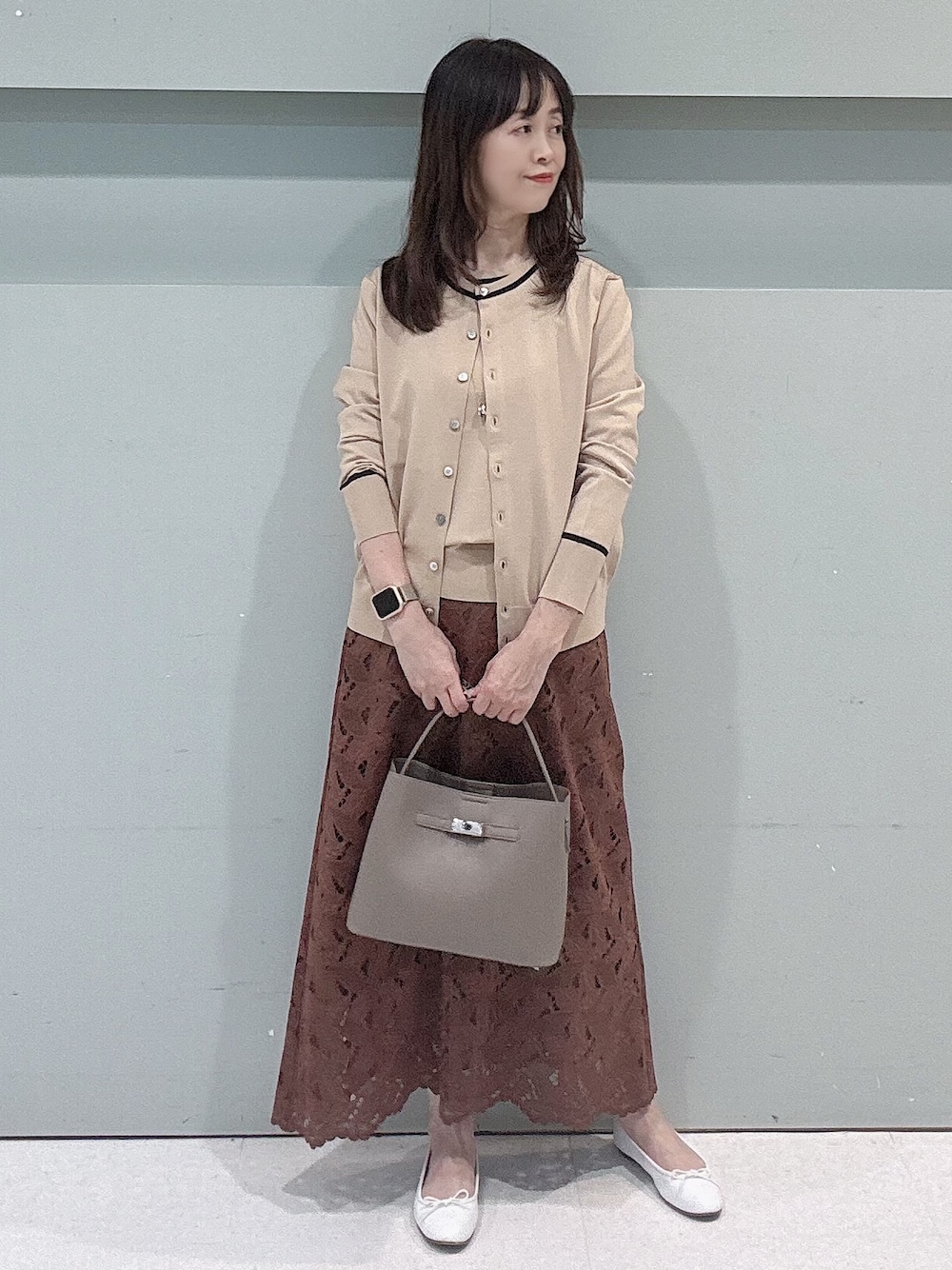 ベージュ系のカーディガン/ボレロ、ベージュ系のニット/セーター、ブラウン系のスカートを着用したレディースの秋コーディネートの2枚目の写真