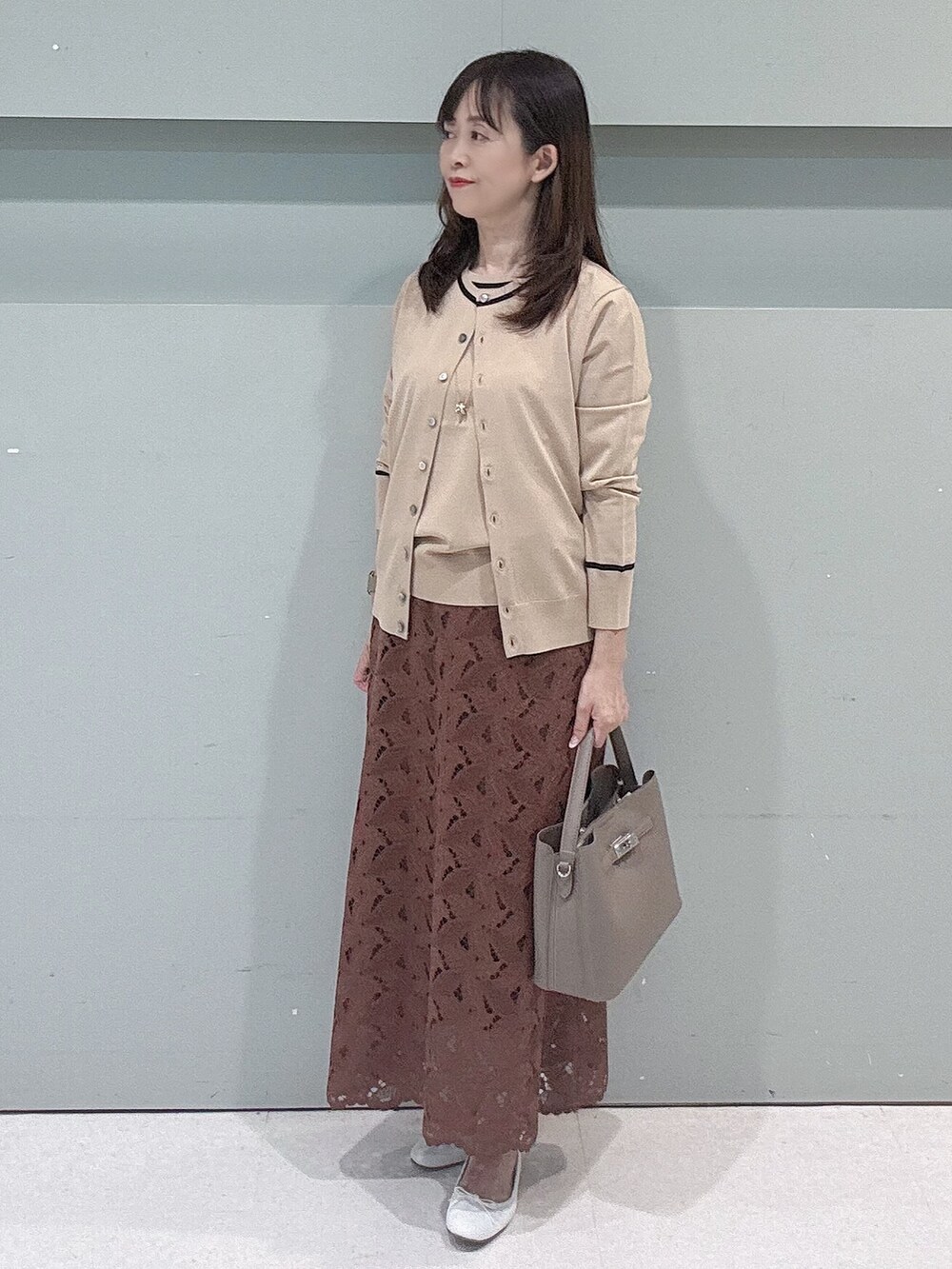 ベージュ系のカーディガン/ボレロ、ベージュ系のニット/セーター、ブラウン系のスカートを着用したレディースの秋コーディネートの4枚目の写真