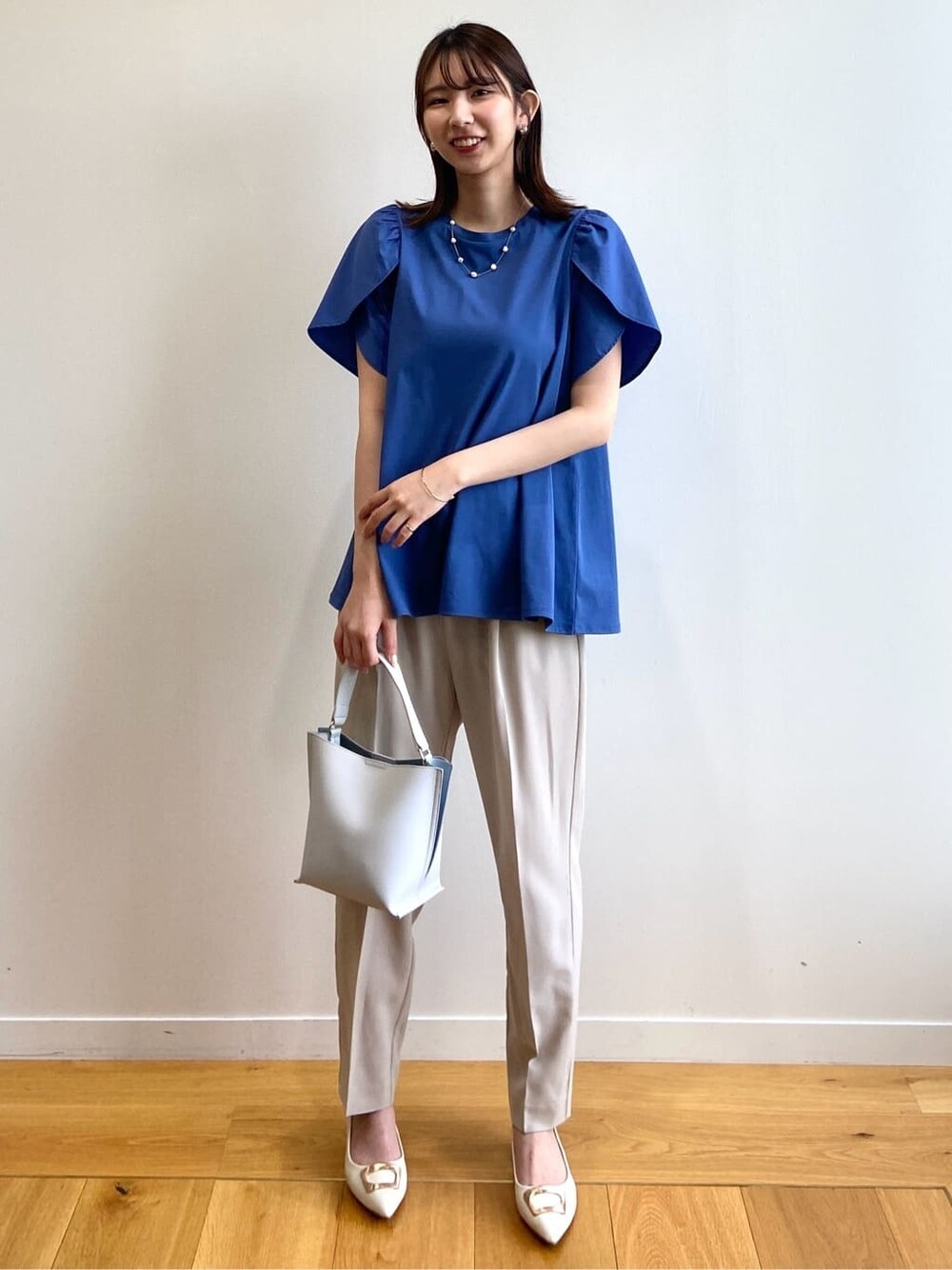ブルー系のTシャツ/カットソー、ベージュ系のその他パンツ、グレー系のショルダーバッグを着用したレディースの春コーディネートの2枚目の写真