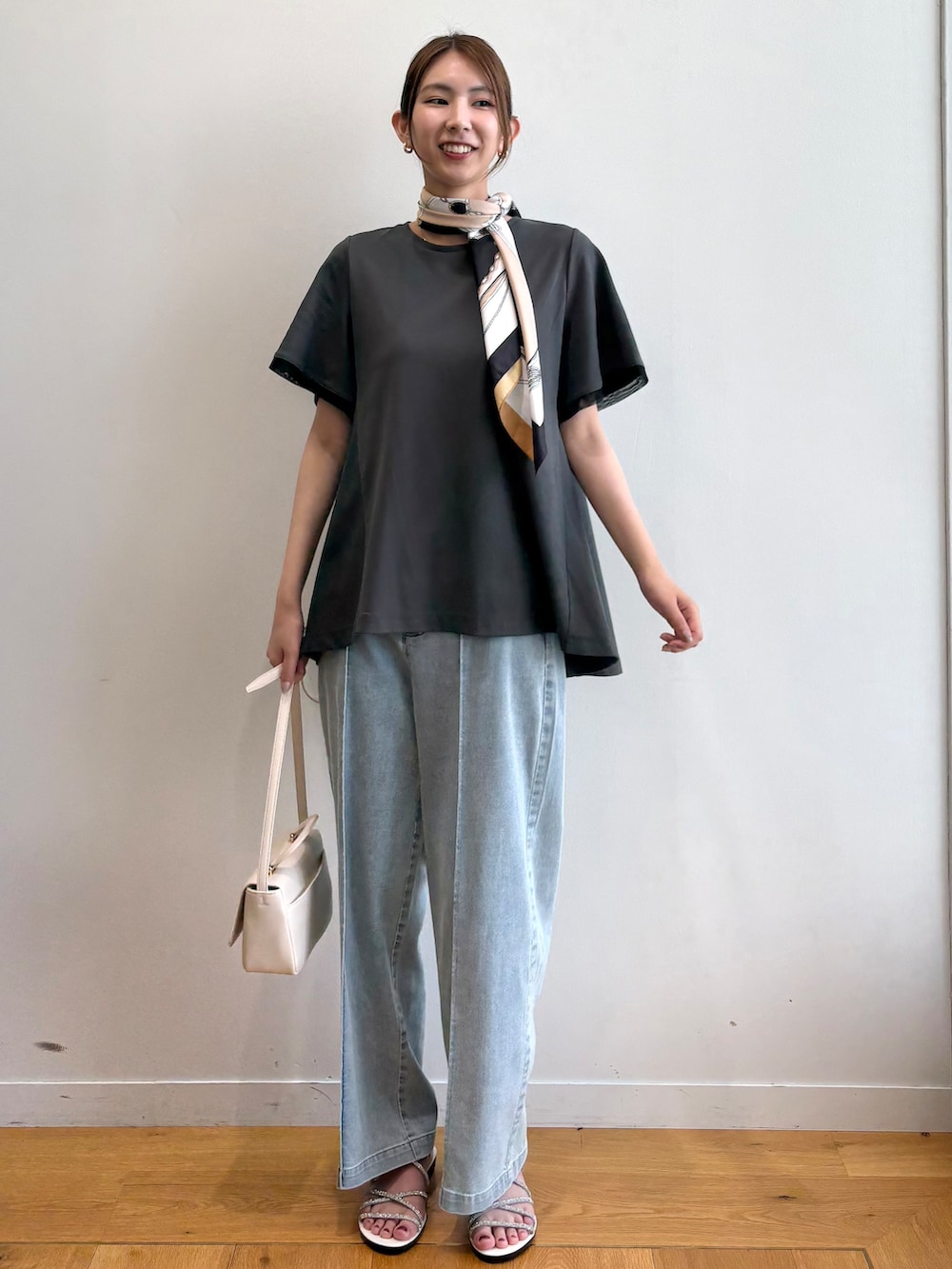 グレー系のTシャツ/カットソー、ブルー系のデニムパンツ、シルバー系のサンダルを着用したレディースの夏コーディネートの2枚目の写真