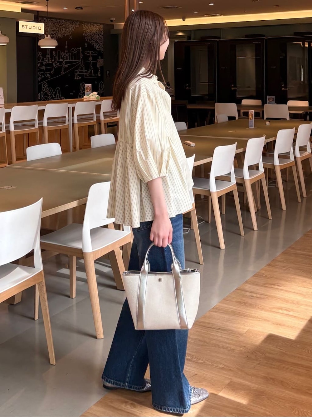 イエロー系のシャツ/ブラウス、ブルー系のデニムパンツ、シルバー系のトートバッグを着用したレディースの春コーディネートの3枚目の写真