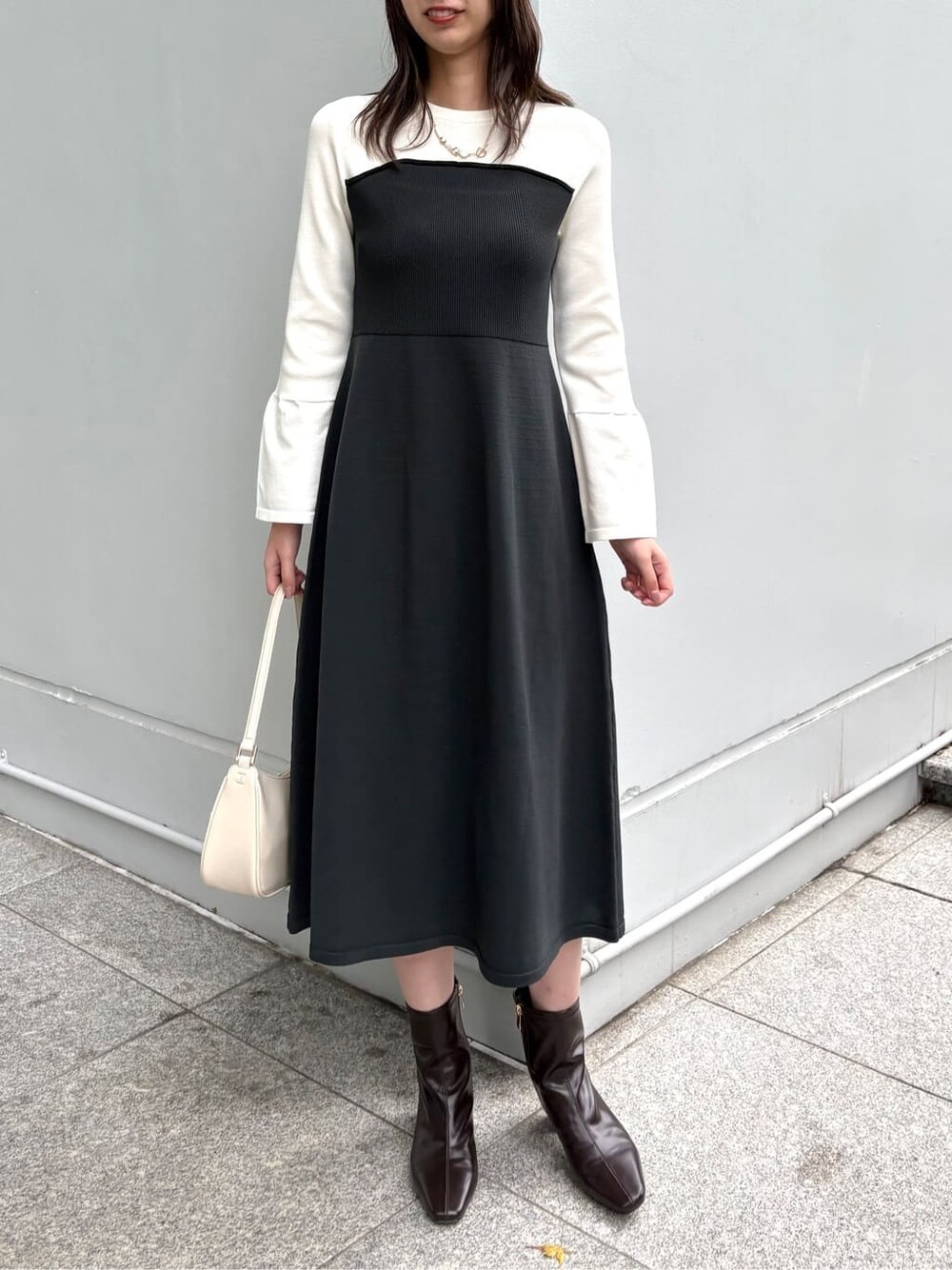 グレー系のワンピース、ホワイト系のショルダーバッグ、ブラウン系のブーツを着用したレディースの冬コーディネートの8枚目の写真