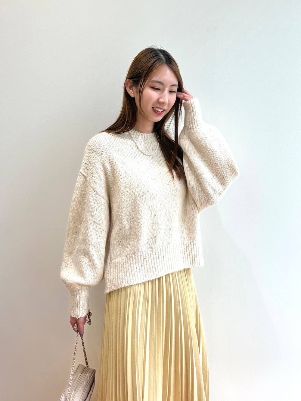 ホワイト系のニット/セーター、イエロー系のスカート、ベージュ系のショルダーバッグを着用したレディースの夏コーディネートの6枚目の写真