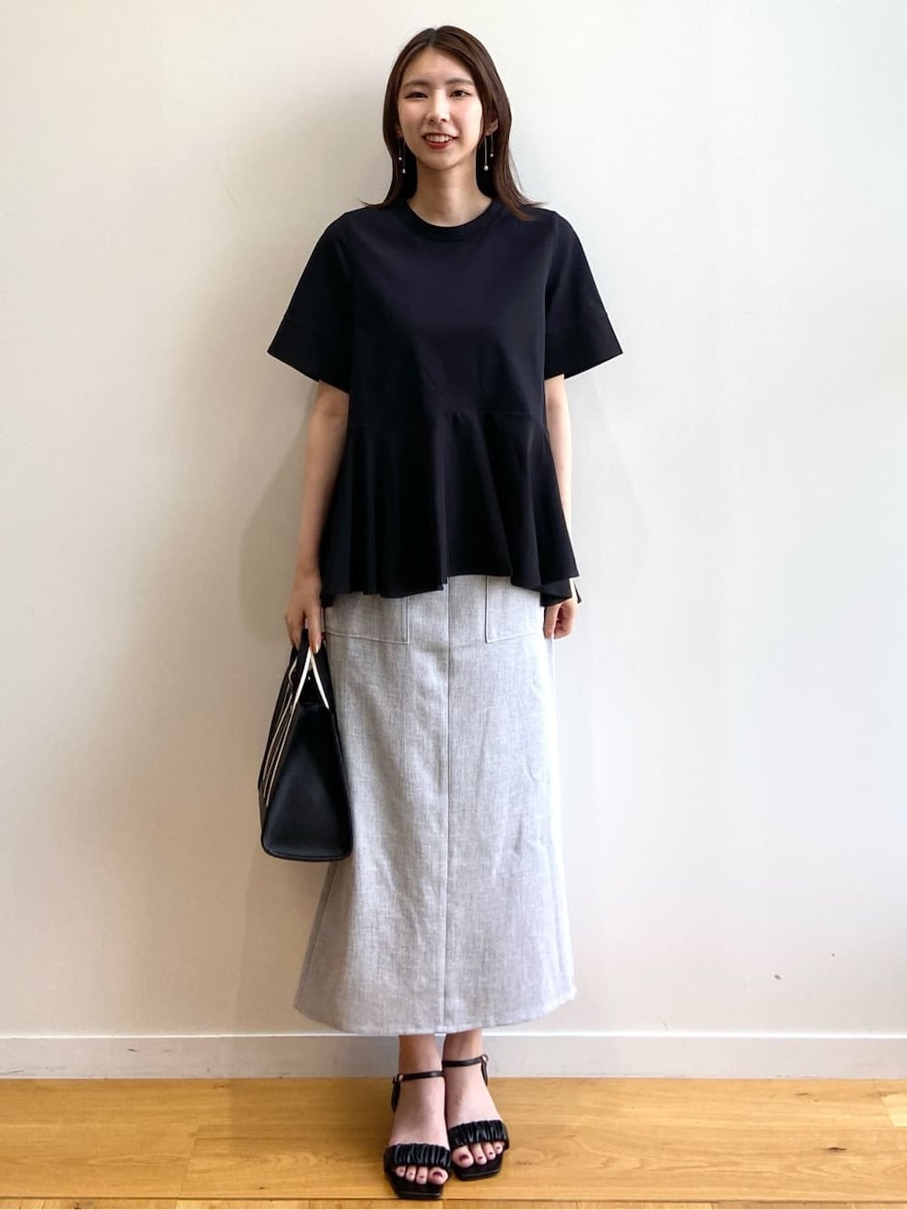 ブラック系のTシャツ/カットソー、グレー系のスカート、ブラック系のサンダルを着用したレディースの夏コーディネートの2枚目の写真