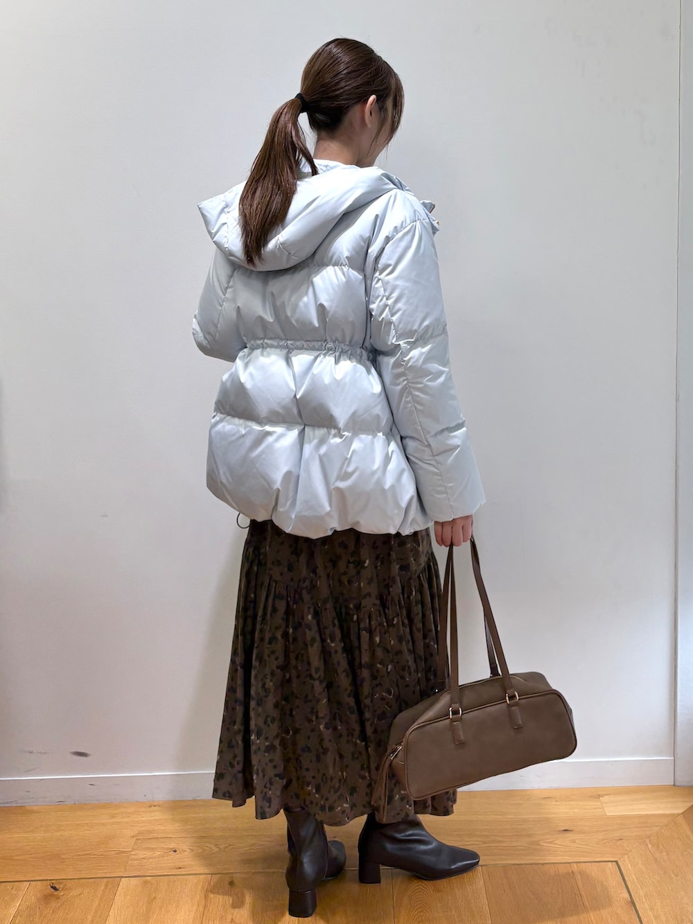 ブルー系のダウンジャケット/コート、ブラック系のニット/セーター、ブラウン系のスカートを着用したレディースの秋コーディネートの6枚目の写真