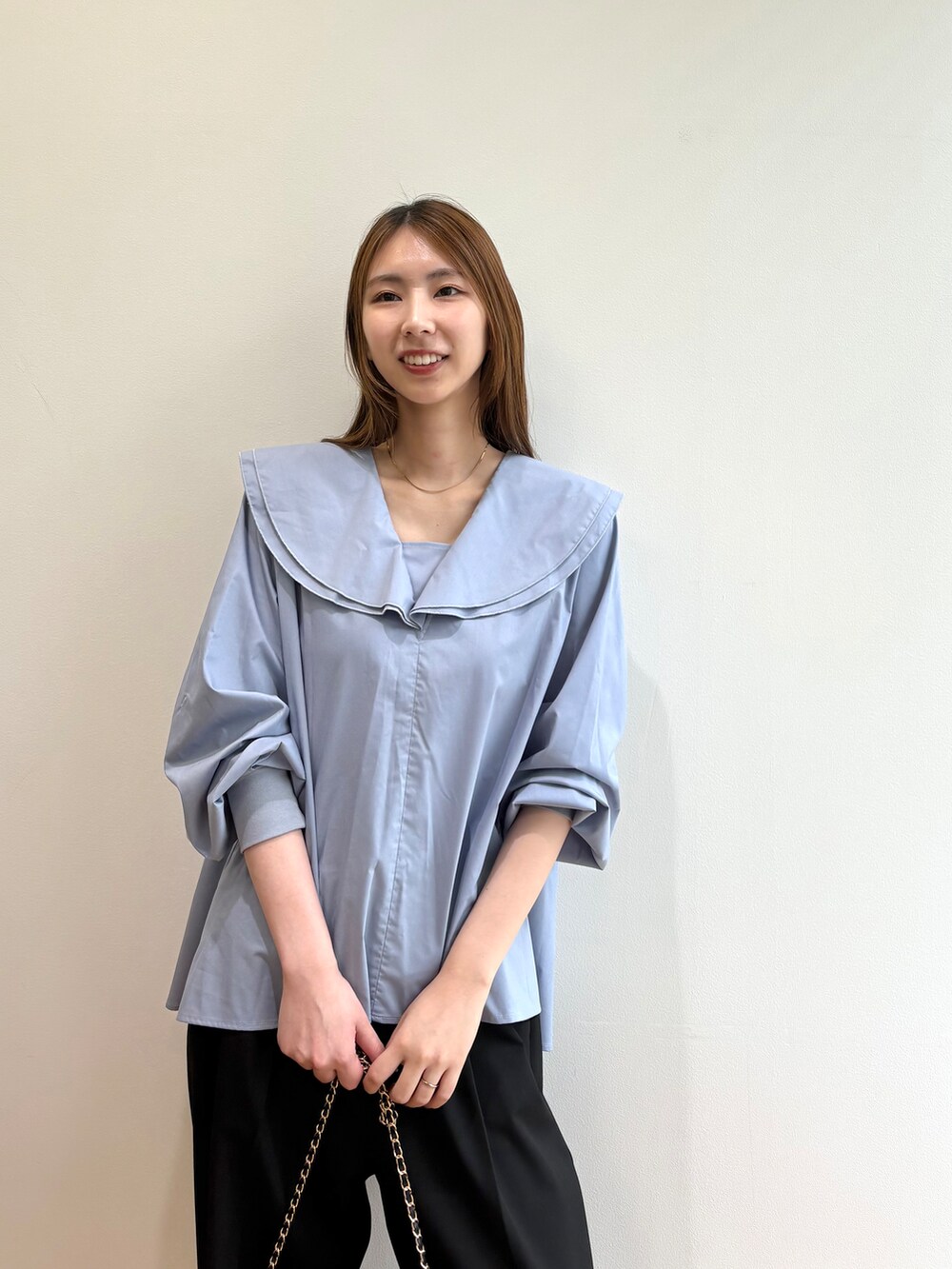 ブルー系のシャツ/ブラウス、ブラック系のショルダーバッグ、ブラック系のパンプスを着用したレディースの夏コーディネートの6枚目の写真