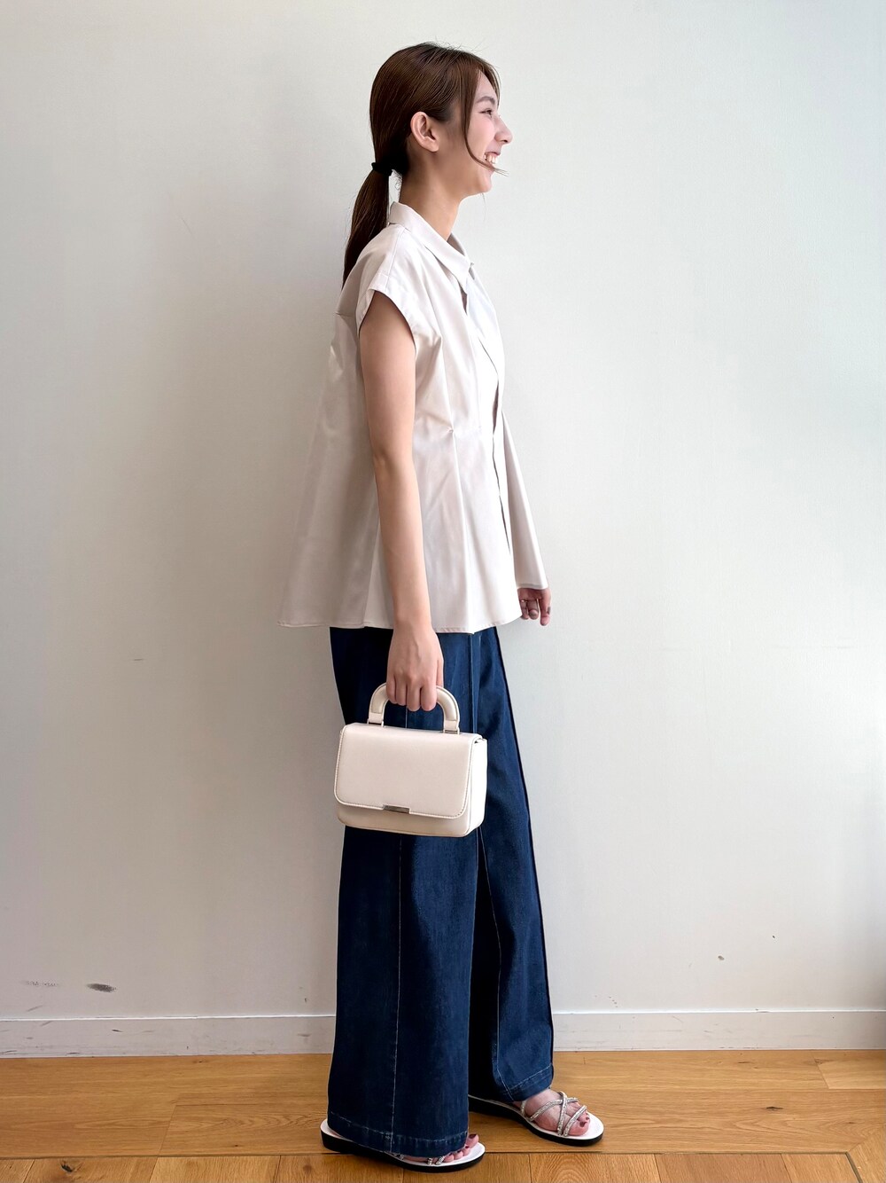 ベージュ系のシャツ/ブラウス、ブルー系のデニムパンツ、ホワイト系のショルダーバッグを着用したレディースの夏コーディネートの4枚目の写真