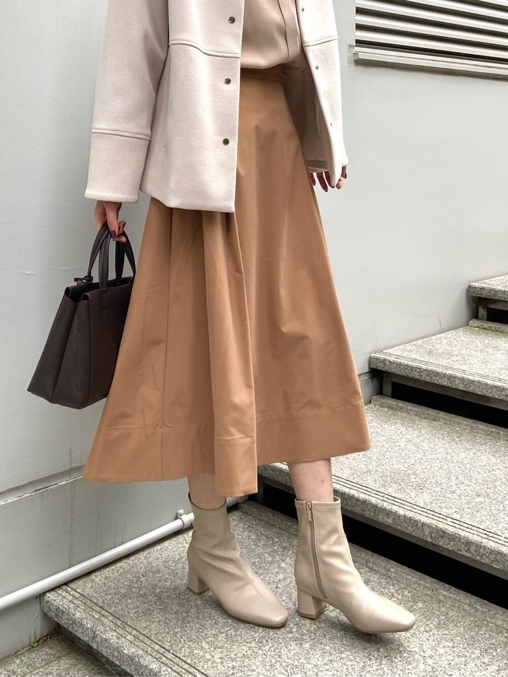 ベージュ系のノーカラーコート、ベージュ系のシャツ/ブラウス、イエロー系のスカートを着用したレディースの秋コーディネートの10枚目の写真