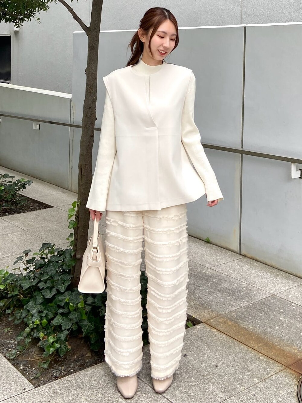 ホワイト系のその他パンツ、ホワイト系のショルダーバッグ、ベージュ系のブーツを着用したレディースの秋コーディネートの2枚目の写真