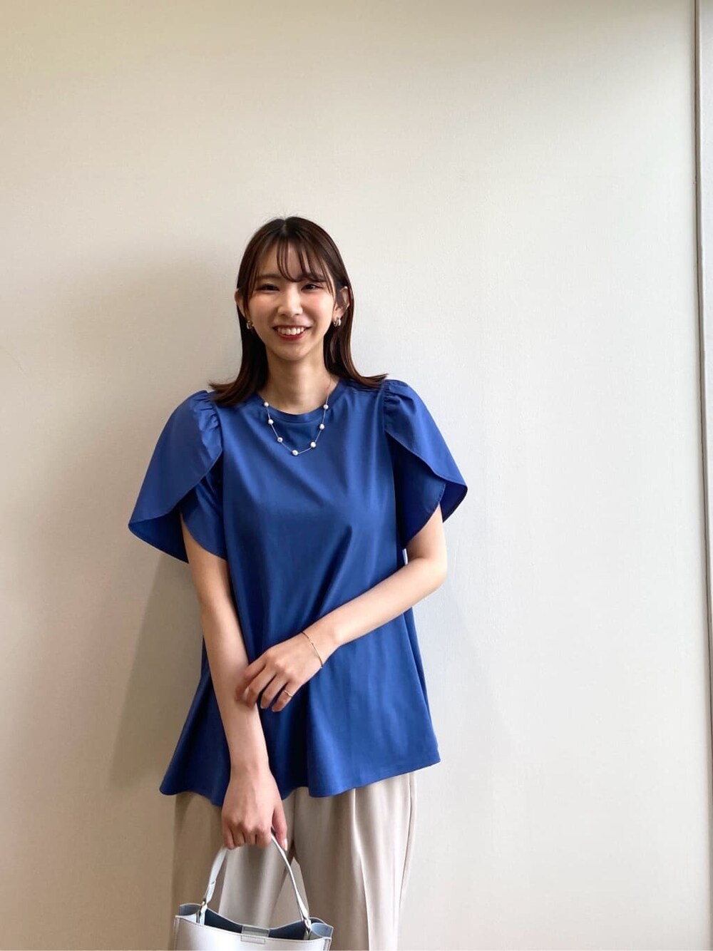 ブルー系のTシャツ/カットソー、ベージュ系のその他パンツ、グレー系のショルダーバッグを着用したレディースの春コーディネートの7枚目の写真