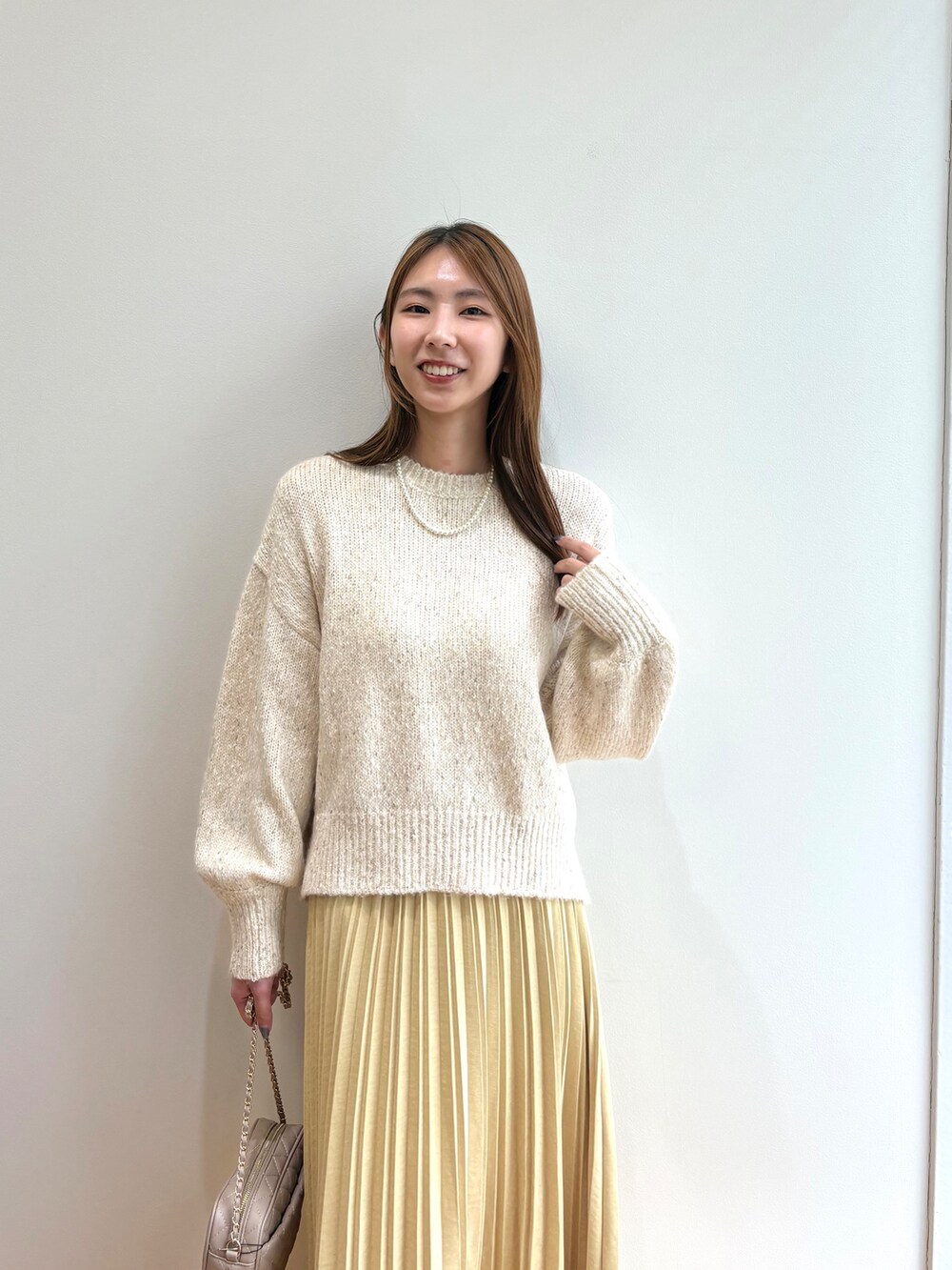 ホワイト系のニット/セーター、イエロー系のスカート、ベージュ系のショルダーバッグを着用したレディースの夏コーディネートの7枚目の写真