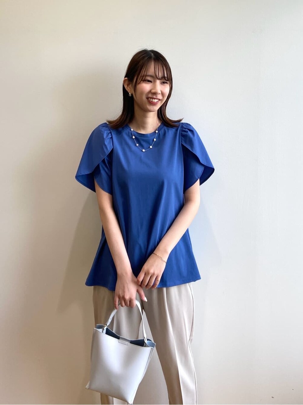 ブルー系のTシャツ/カットソー、ベージュ系のその他パンツ、グレー系のショルダーバッグを着用したレディースの春コーディネートの6枚目の写真