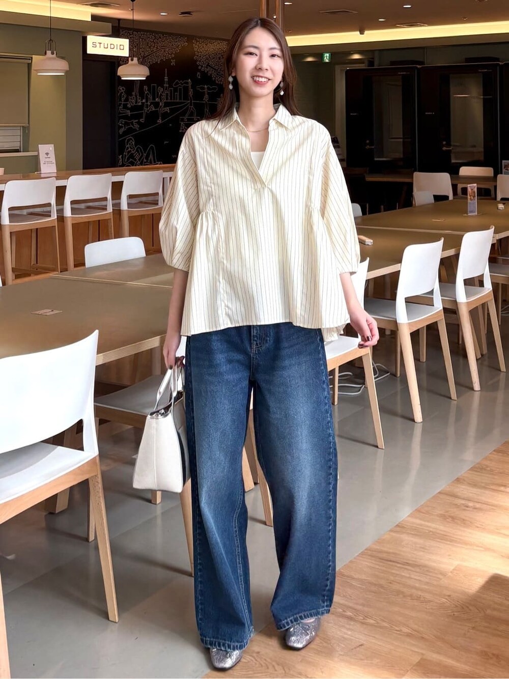 イエロー系のシャツ/ブラウス、ブルー系のデニムパンツ、シルバー系のトートバッグを着用したレディースの春コーディネートの2枚目の写真