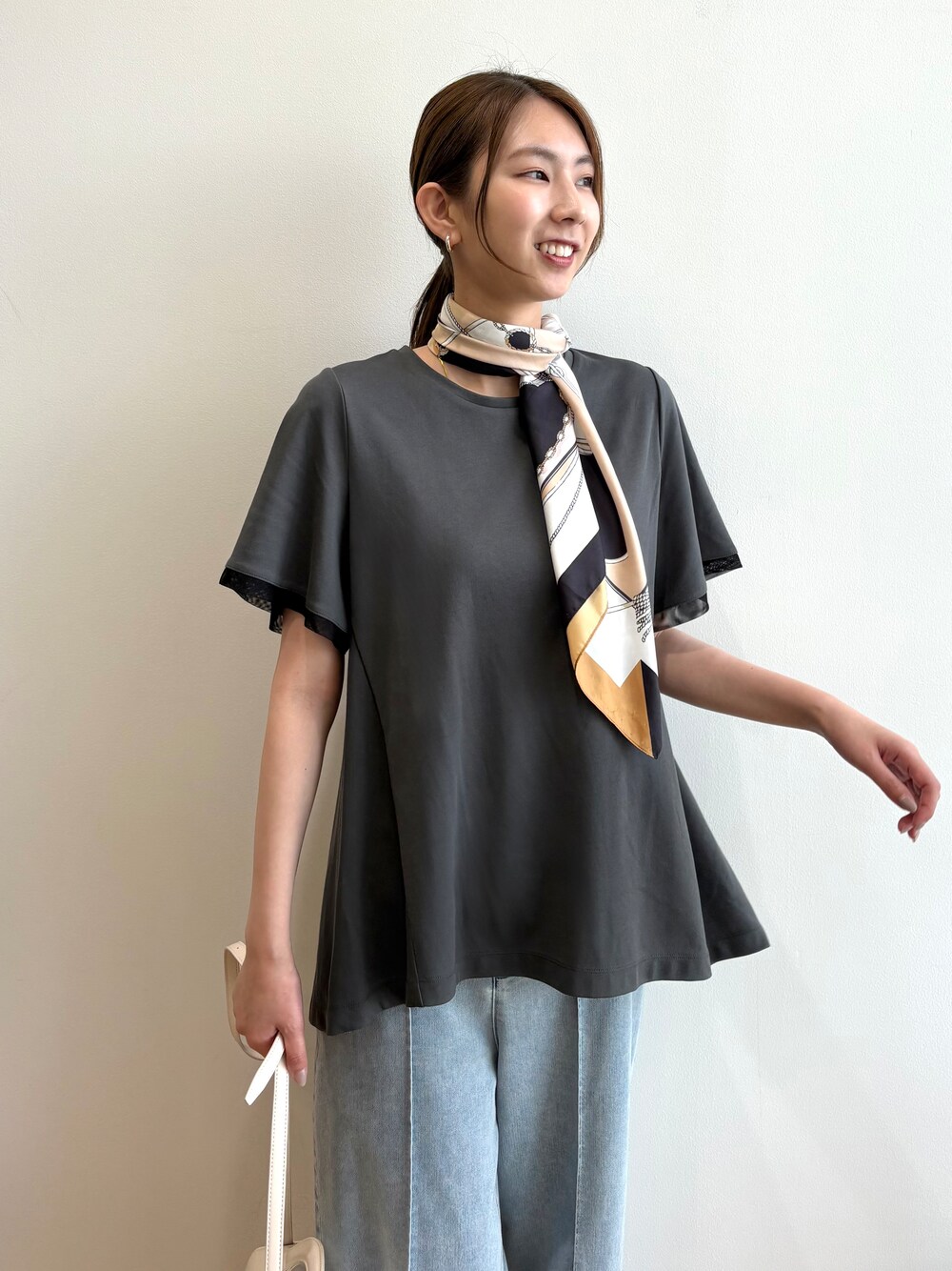 グレー系のTシャツ/カットソー、ブルー系のデニムパンツ、シルバー系のサンダルを着用したレディースの夏コーディネートの6枚目の写真