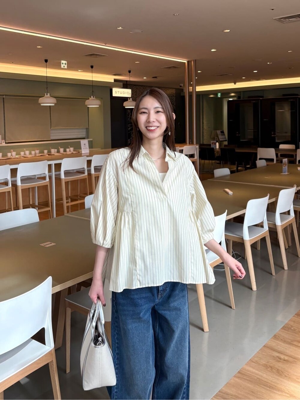 イエロー系のシャツ/ブラウス、ブルー系のデニムパンツ、シルバー系のトートバッグを着用したレディースの春コーディネートの6枚目の写真