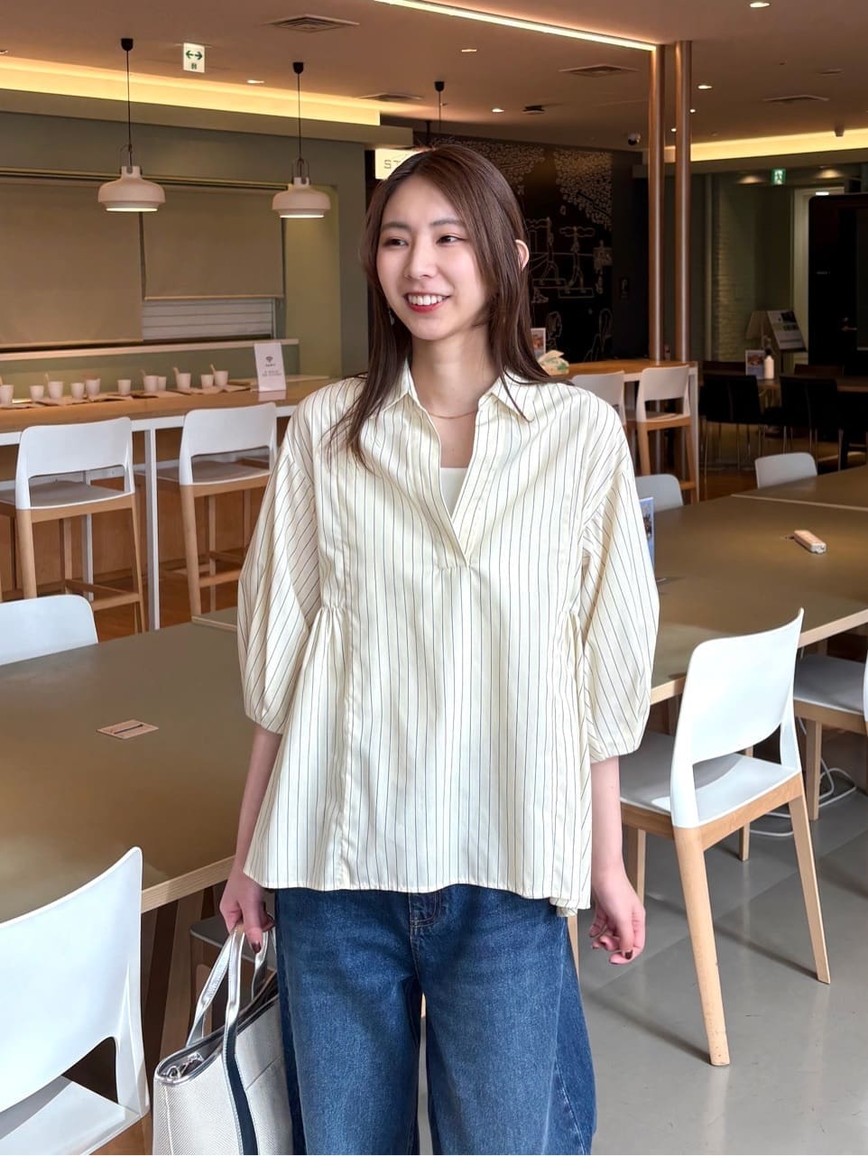 イエロー系のシャツ/ブラウス、ブルー系のデニムパンツ、シルバー系のトートバッグを着用したレディースの春コーディネートの7枚目の写真