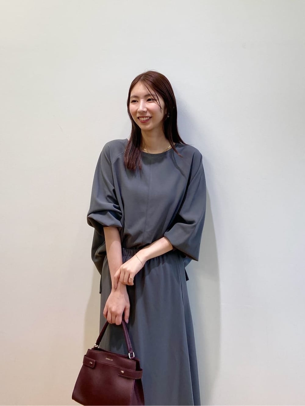 グレー系のセットアップ、レッド系のショルダーバッグ、レッド系のパンプスを着用したレディースの秋コーディネートの8枚目の写真