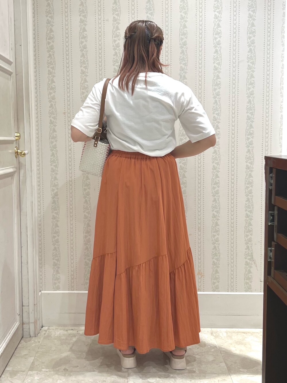 ホワイト系のTシャツ/カットソー、オレンジ系のスカート、レッド系のショルダーバッグを着用したレディースの春コーディネートの3枚目の写真