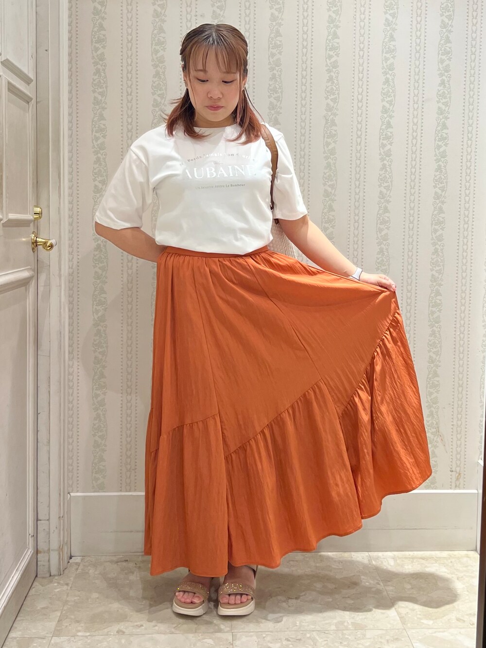ホワイト系のTシャツ/カットソー、オレンジ系のスカート、レッド系のショルダーバッグを着用したレディースの春コーディネートの4枚目の写真