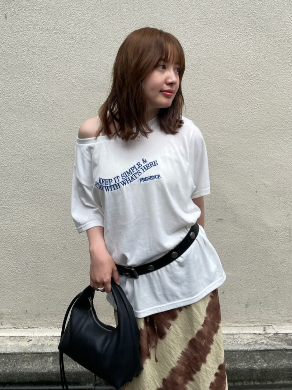 ブラウン系のスカート、ブラック系のハンドバッグ、ホワイト系のTシャツ/カットソーを着用したレディースの夏コーディネートの4枚目の写真