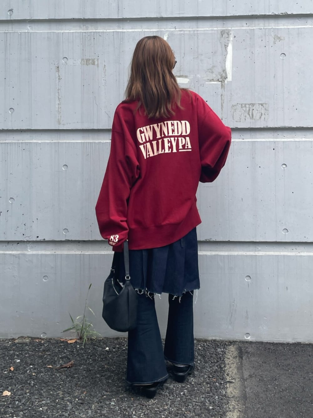 ブラック系のその他シューズ、ブルー系のデニムパンツ、レッド系のスウェットを着用したレディースの秋コーディネートの3枚目の写真