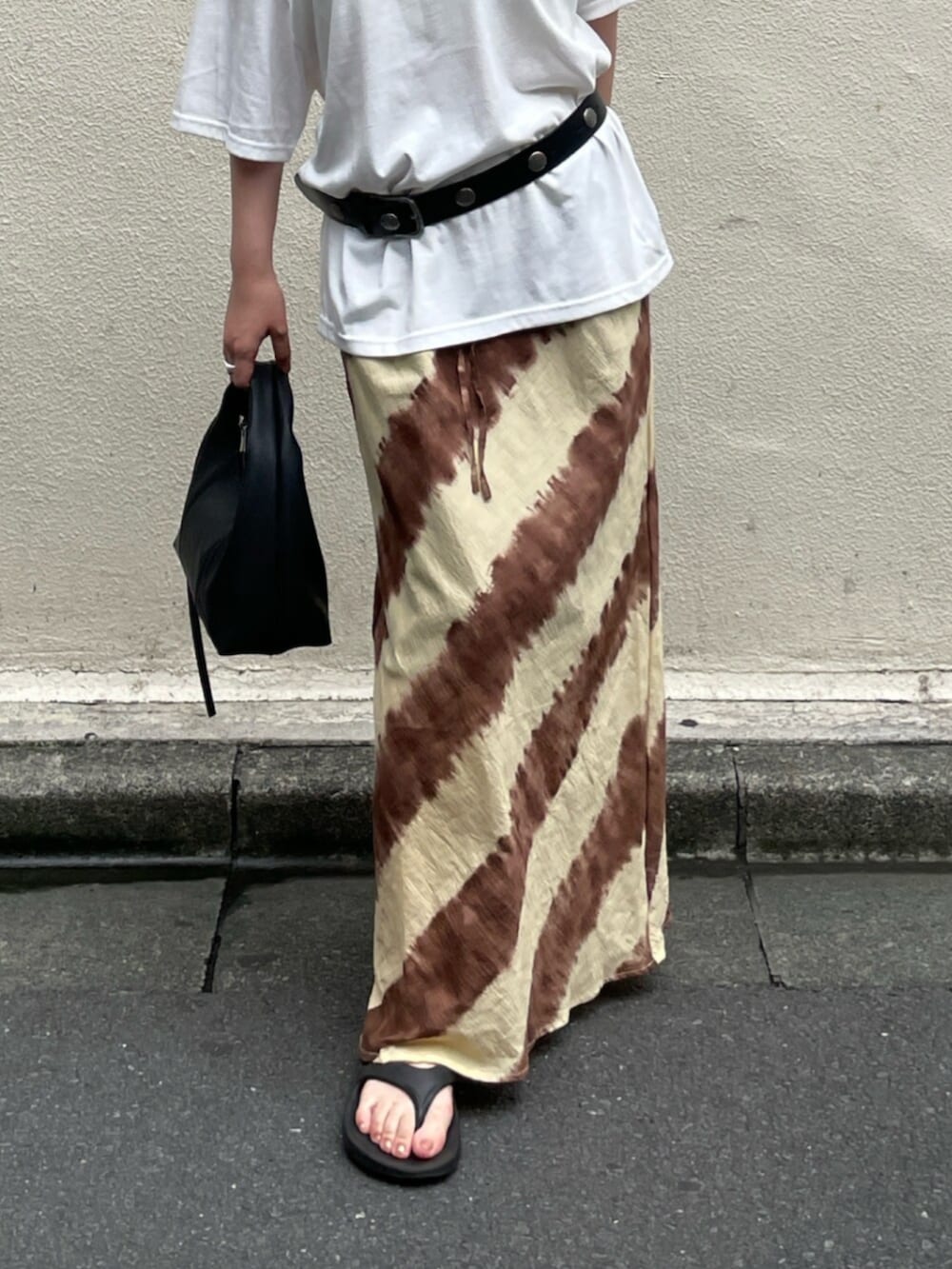 ブラウン系のスカート、ブラック系のハンドバッグ、ホワイト系のTシャツ/カットソーを着用したレディースの夏コーディネートの5枚目の写真