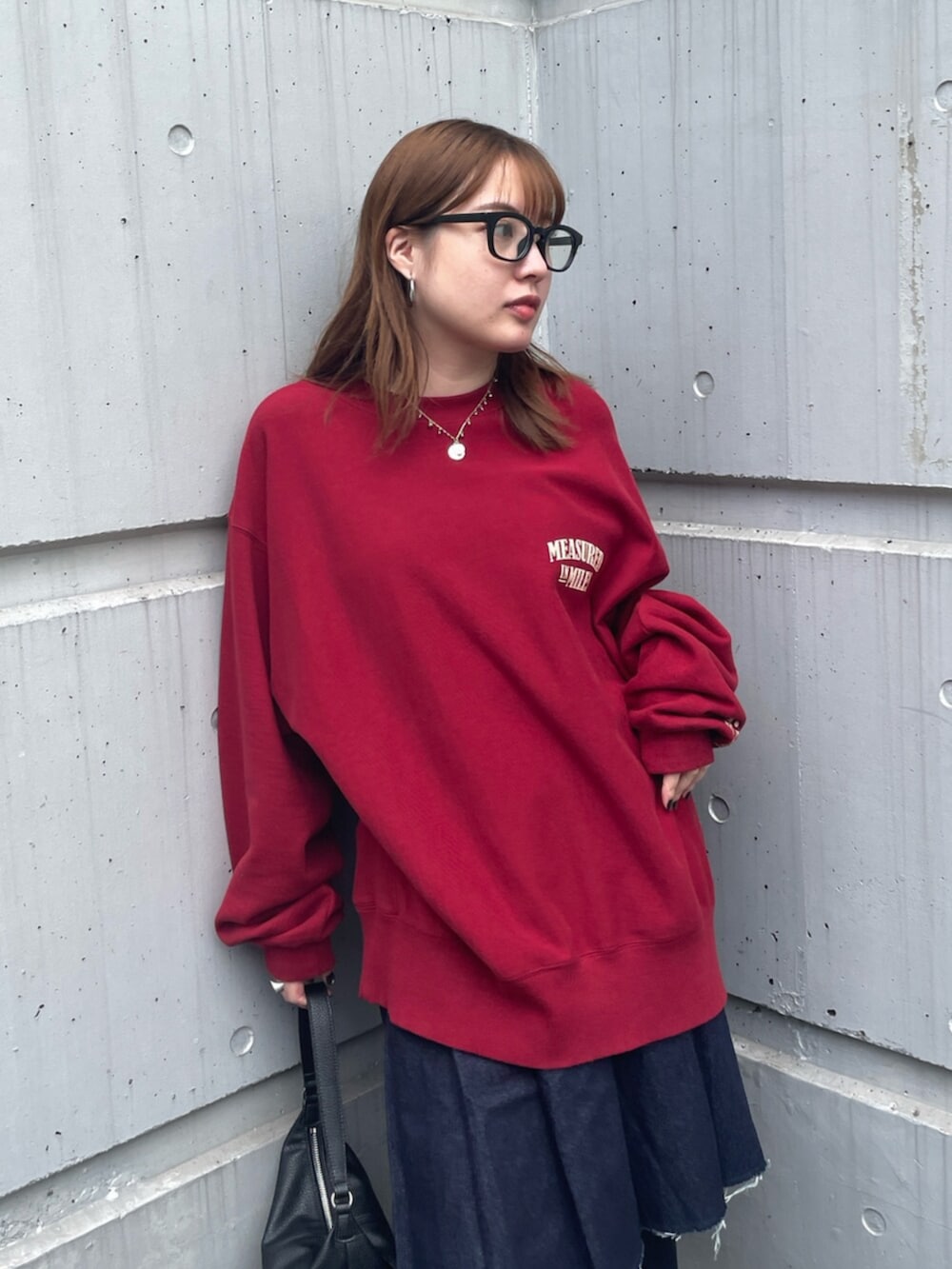 ブラック系のその他シューズ、ブルー系のデニムパンツ、レッド系のスウェットを着用したレディースの秋コーディネートの4枚目の写真