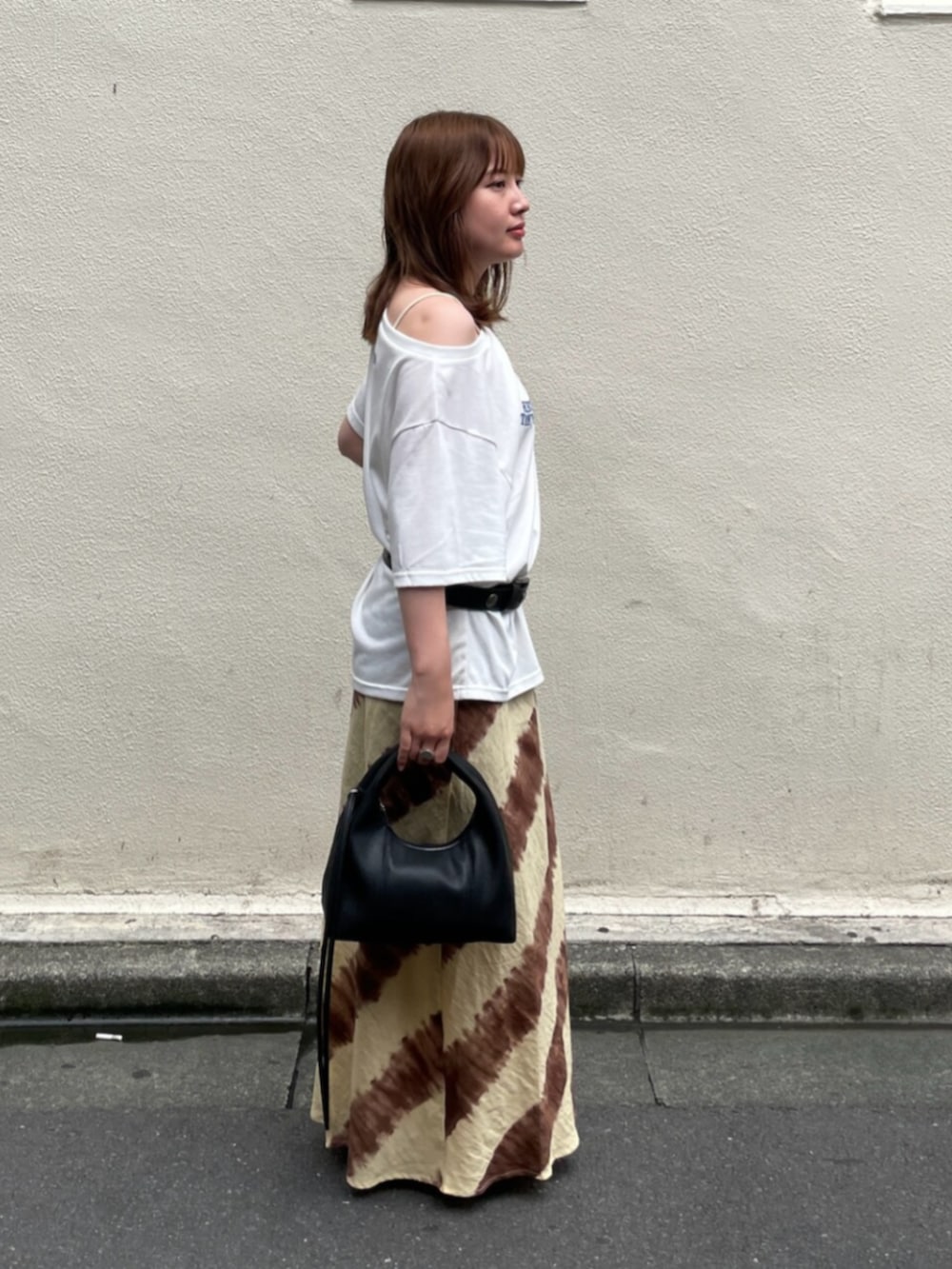 ブラウン系のスカート、ブラック系のハンドバッグ、ホワイト系のTシャツ/カットソーを着用したレディースの夏コーディネートの2枚目の写真