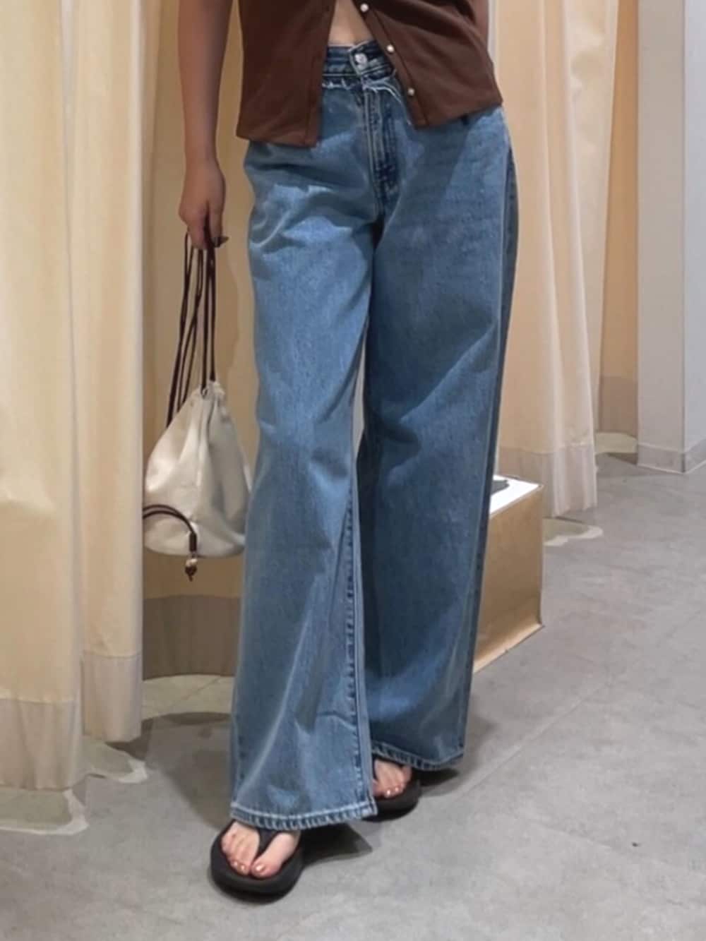 ブルー系のデニムパンツ、ホワイト系のショルダーバッグ、ブラウン系のTシャツ/カットソーを着用したレディースの夏コーディネートの5枚目の写真