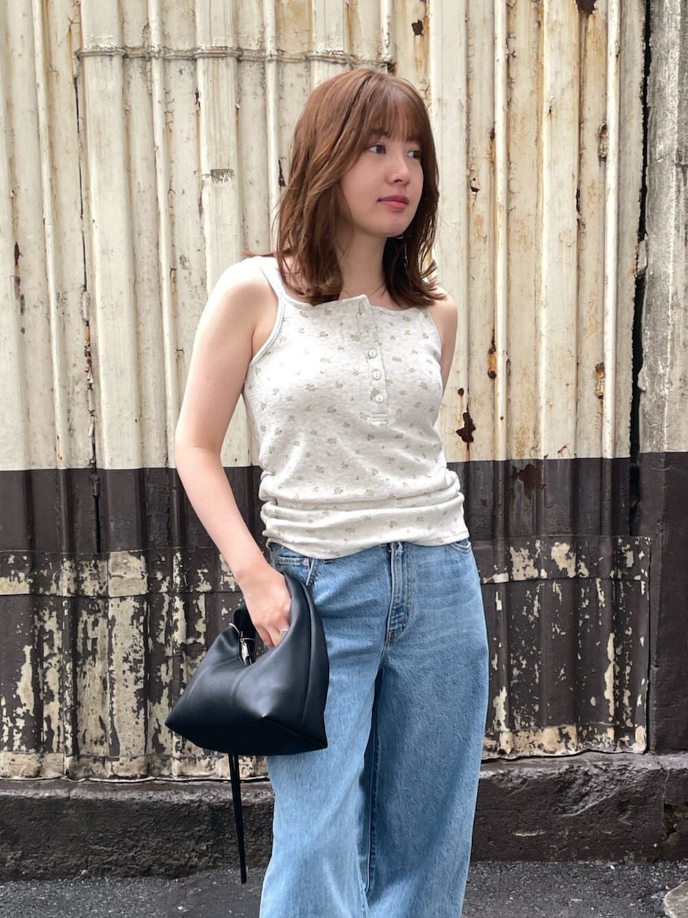 ブラック系のハンドバッグ、ブルー系のデニムパンツ、グレー系のキャミソールを着用したレディースの夏コーディネートの5枚目の写真